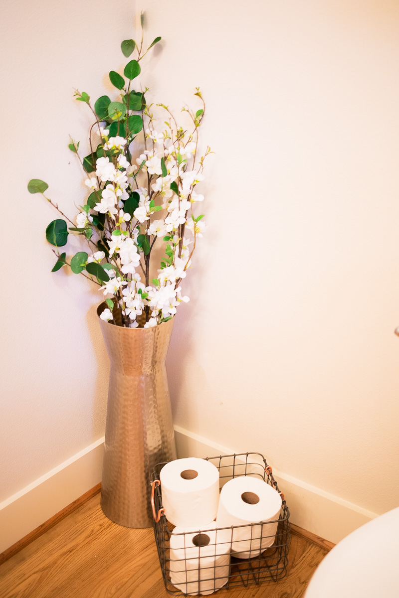 modern bathroom decor sink flowers in vase, toilet paper in wire basket