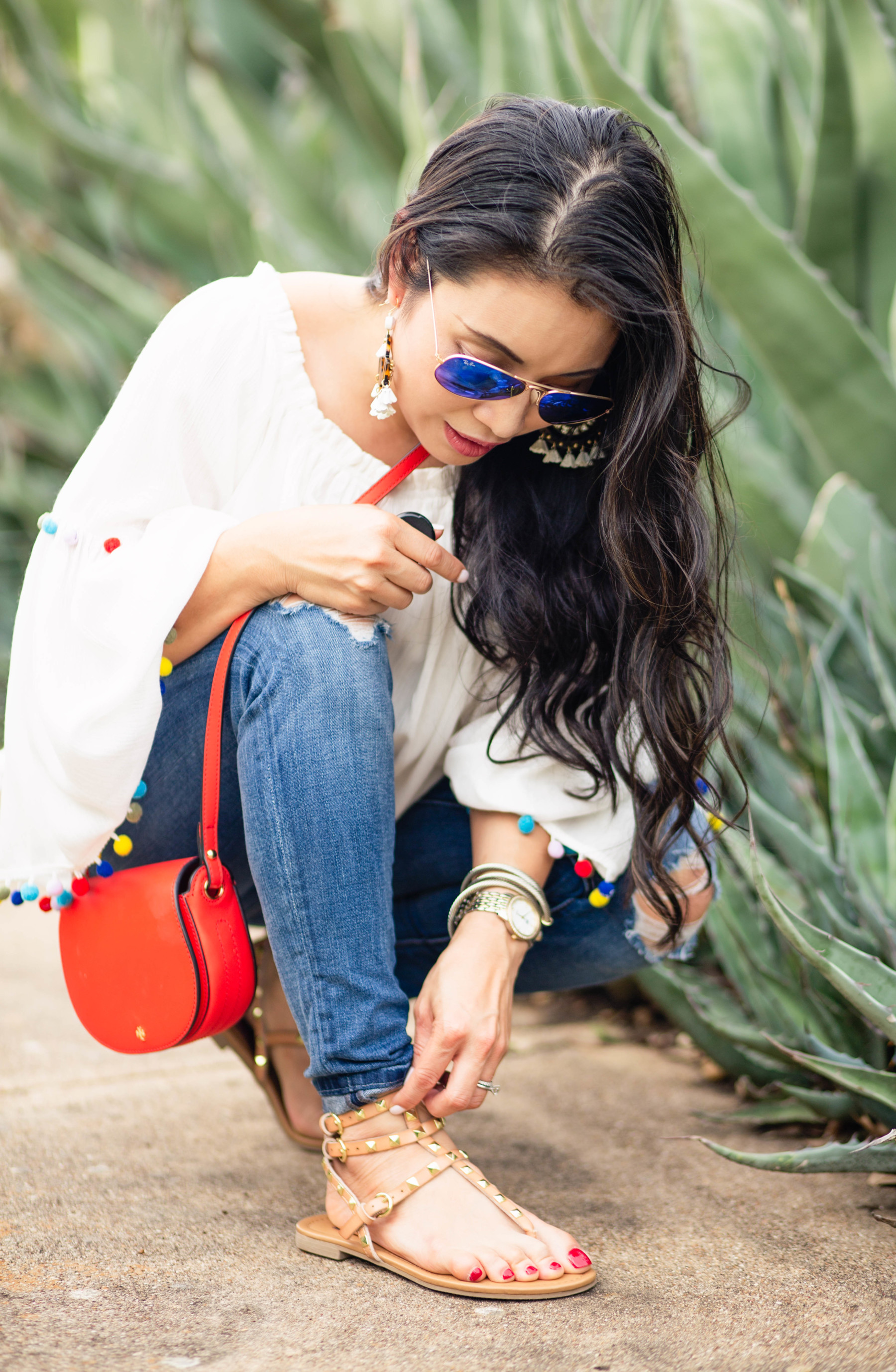 petite fashion blog| white pom pom blouse, distressed jeans, valentino dupe studded thong sandals, tory burch red mini saddle bag | summer outfit