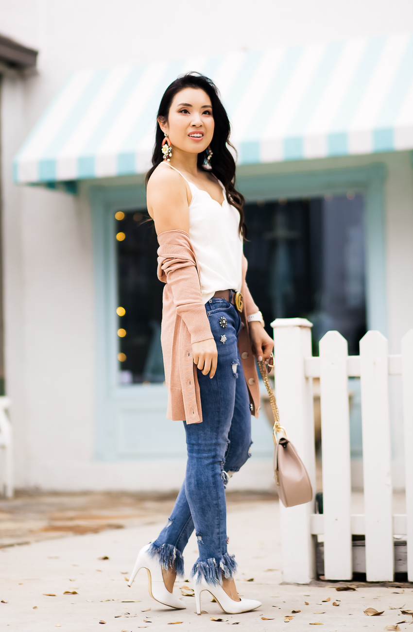 cute & little | dallas petite fashion blog | pink cardigan, scallop cami, express embellished fringe skinny jeans, gucci belt, statementn earrings | spring outfit - Raw Hem Jeans and All The Hem Details by popular Dallas petite fashion blogger cute & little