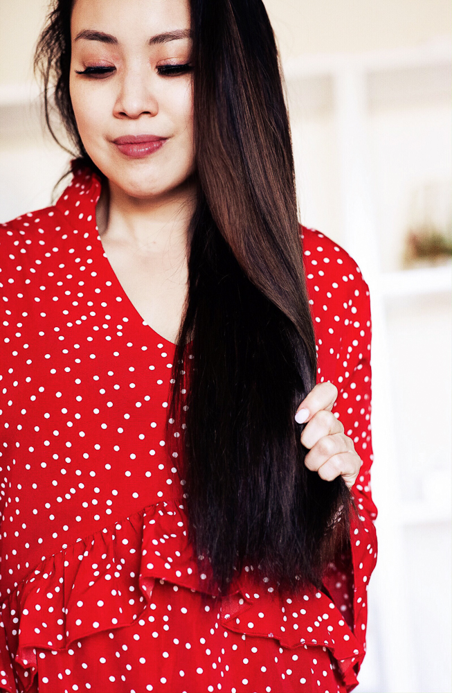 Valentine's Hairstyle featured by top US beauty blog Cute & Little; Image of woman in a red blouse doing her hair.