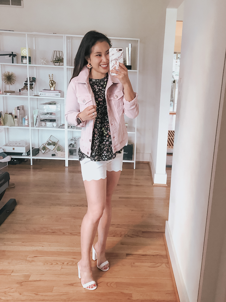 cute & little | dallas petite fashion blog | loft march haul try-on review | loft blush pink denim jacket, loft garden cutout peplum top, white scallop shorts, white slip on mule sandals | spring casual outfit | LOFT favorites: March Try On featured by top US petite fashion blog, Cute & Little; Image of woman wearing a LOFT Modern Denim Jacket, LOFT Garden Cutout Back Peplum Top, LOFT White Scalloped Shorts, J.Crew earrings, ASOS shoes, Fitbit 'Versa' w/ watch band and a Red Dress Boutique 'It's A Staple' Straw Tote