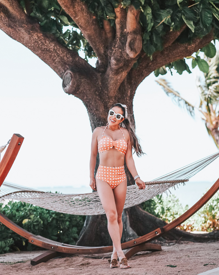 cute & little | popular dallas petite fashion travel blog | amazon cupshe high-waisted mom friendly peach scallop bikini | molokai maui beach | Affordable Fashion: Cute Summer Swimsuits you Need by popular Dallas blog Cute and Little: Image of a woman in Maui, Hawaii standing outside in front of a hammock under a tree and wearing a Amazon Cupshe Peach Polka Dot Bikini, Baublebar 'Brianna' Heart Hoops, Amazon Striped Knot Headband, Etsy Solitaire 15" necklace, Fitbit 'Versa' smartwatch and Tori Burch Miller sandals. 
