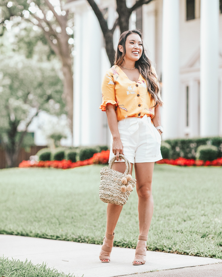 Ann Taylor Cyber Sale featured by top US petite fashion blog Cute & Little; Image of a woman wearing walmart fashion yellow floral ruffle blouse, ann taylor marina tie waist white shorts, steve madden jelly nude strappy sandals and walmart eliza may rose straw pom pom bag. 