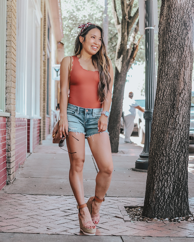 Flattering Shorts featured by top US petite fashion blog Cute & Little; Image of a woman wearing blanknyc astor shorts, topshop scallop one-shoulder bodysuit swimsuit, target sincerely jules headwrap, target studded aviator sunglasses and see by chloe wedges.