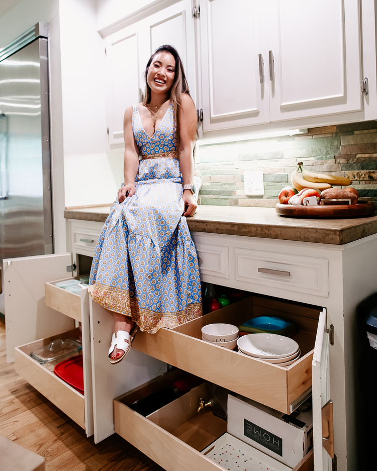 cute & little | popular dallas home blogger | shelfgenie home improvement organization review | quick and easy tips to organize your kitchen | Quick Kitchen Organization Tips with ShelfGenie by popular Dallas petite fashion blog, Cute and Little: image of a woman in her kitchen sitting on top of her kitchen counter with her ShelfGenie drawers pulled out and wearing J.Crew Tiered Maxi, Panacea Gold Circle Layered Necklace, and Steve Madden 'Greece' Slides. 