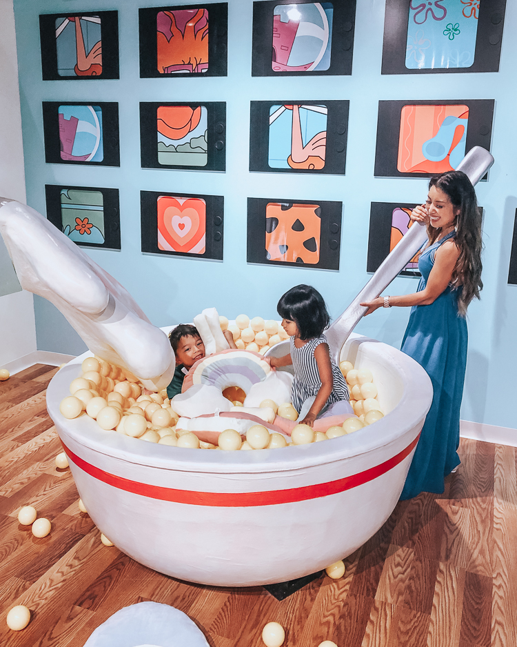 cute & little | popular dallas fashion mom blog | museum of memories instagram popup immersive art exhibit |  Take a Selfie of Your Childhood: Museum of Memories by popular Dallas blog Cute and Little: image of woman and a boy and girl paying in an interactive life size bowl of cereal at the Museum of Memories.  Woman is wearing Gibson x Hi Sugarplum! Santorini Maxi, Marc Fisher 'Robbyn' Espadrilles, and Panacea Shell Rope Hoops.