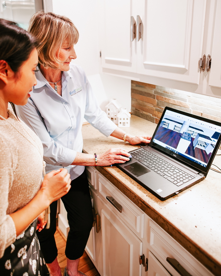 cute & little | popular dallas home blogger | shelfgenie home improvement organization review | quick and easy tips to organize your kitchen | Quick Kitchen Organization Tips with ShelfGenie by popular Dallas petite fashion blog, Cute and Little: image of a woman in her kitchen with a shelfgenie consultant looking at her new shelfgenie installation on a laptop.