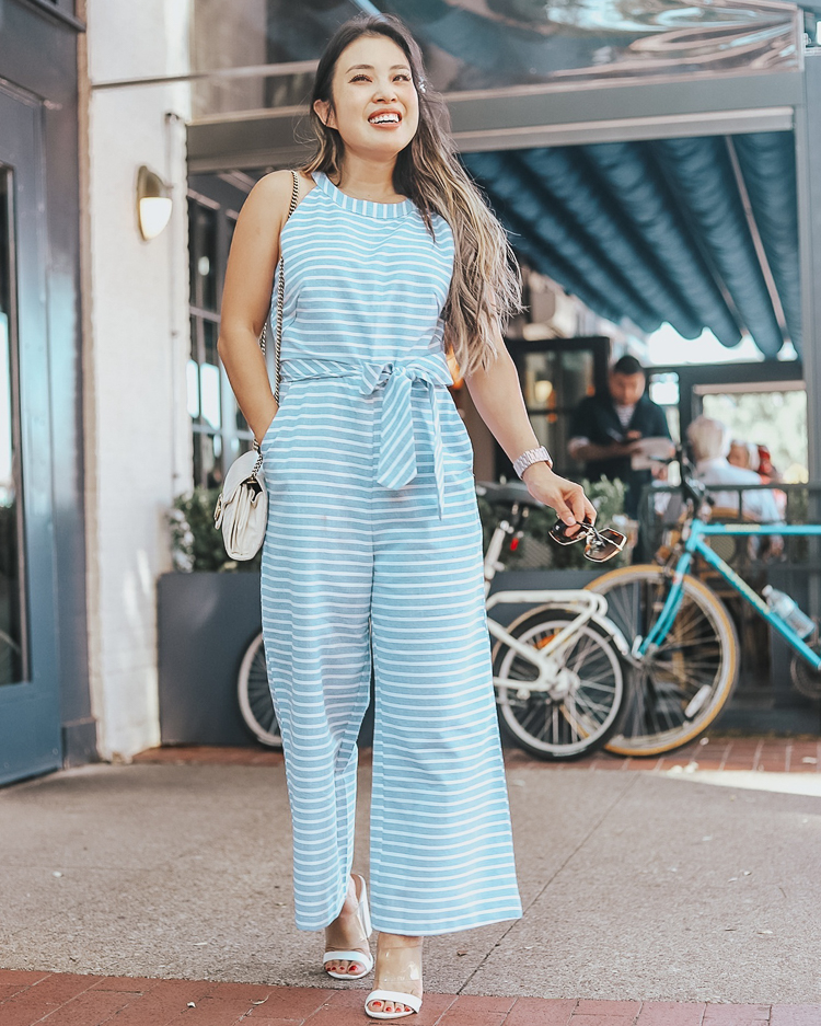 cute & little | popular dallas fashion blog | amazon stripe blue wide leg halter jumpsuit | style for every body | summer outfit | Style For Every Body: Cute Summer Jumpsuits by popular Dallas petite fashion blog, Cute and Little: image of woman standing outside in front of some bicycles and wearing a blue PRETTYGARDEN 2019 Women's Striped Sleeveless Waist Belted Zipper Back Wide Leg Loose Jumpsuit Romper with Pockets.
