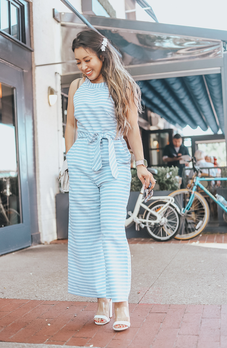 cute & little | popular dallas fashion blog | amazon stripe blue wide leg halter jumpsuit | style for every body | summer outfit | Style For Every Body: Cute Summer Jumpsuits by popular Dallas petite fashion blog, Cute and Little: image of woman standing outside in front of some bicycles and wearing a blue PRETTYGARDEN 2019 Women's Striped Sleeveless Waist Belted Zipper Back Wide Leg Loose Jumpsuit Romper with Pockets.