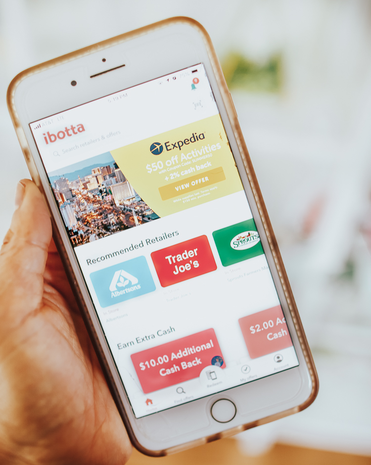 cute & little | popular dallas travel blog | how to save money on travel | ibotta how-to review | 5 Ways I Save Money On Travel by popular Dallas travel blog, Cute and Little: image of a hand holding a smart phone that is open to ibotta app page.