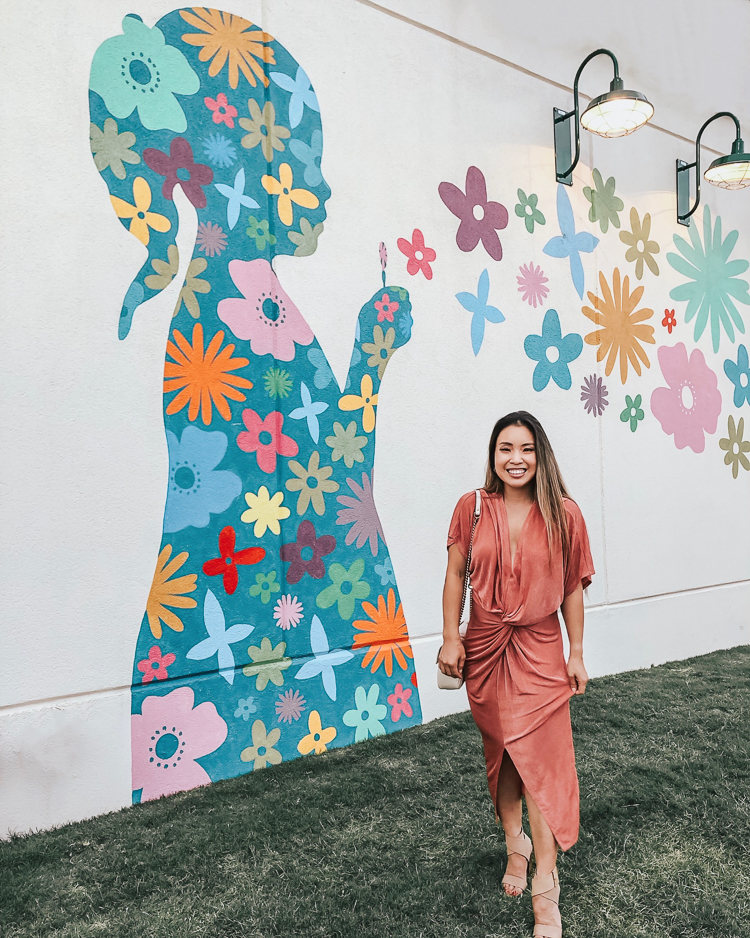 cute & little | popular dallas fashion blog | dallas mural guide | instagram walls | flowerchild blowing flowers wall | Dallas Mural Guide: Top 10 Instagram Walls by popular Dallas blog, Cute and Little: image of a woman standing in front of a flower child mural and wearing a Amazon twist front midi dress, Splendid Jayla shoes, and Gucci Small Marmont bag.
