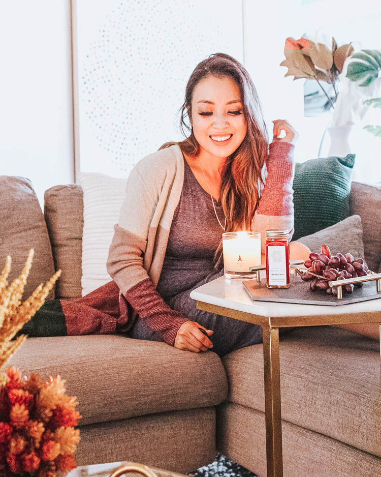 cute & little | popular dallas petite fashion lifestyle blog | how to decorate for fall on a budget | trapp fragrance candles discount code | How to Get Beautiful Fall Home Decor on a Budget by popular Dallas life and style blog, Cute and Little: image of a woman sitting inside next to a lit Trapp candle.