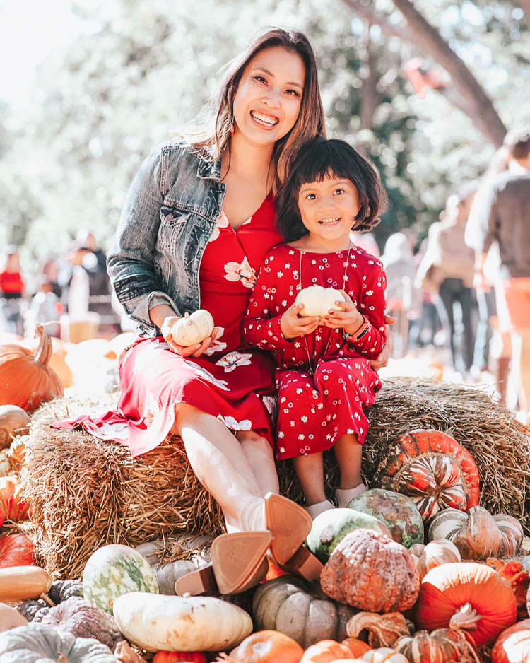 cute & little | popular dallas fashion blog | fall pumpkin patch family photo outfit ideas | What To Wear For Fall Family Photos by popular Dallas petite fashion blog, Cute and Little: image of family getting their fall family photos taken in a pumpkin patch and wearing an Old Navy Waist-Defined Faux-Wrap Jersey Dress for Women, Nordstrom Madewell Denim Jacket, Nordstrom Vince Camuto Gigietta Bootie, Old Navy Fit & Flare Jersey Dress for Toddler Girls, Old Navy Faux-Suede Ankle Boots for Toddler Girls, Old Navy Built-In Flex Pocket Shirt for Boys, Nordstrom Tucker + Tate Flex Pull-On Jeans, Old Navy Faux-Suede/Faux-Leather Sneakers for Boys, Old Navy Slim-Fit Built-In Flex Everyday Shirt for Men, and J. Crew 484 Slim-fit jean in stretch dark worn in Japanese denim.
