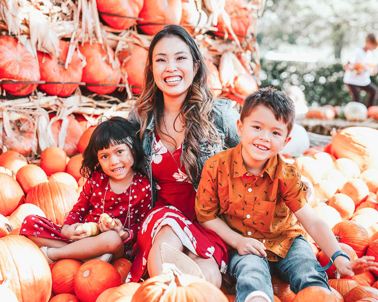 cute & little | popular dallas fashion blog | fall pumpkin patch family photo outfit ideas | What To Wear For Fall Family Photos by popular Dallas petite fashion blog, Cute and Little: image of family getting their fall family photos taken in a pumpkin patch and wearing an Old Navy Waist-Defined Faux-Wrap Jersey Dress for Women, Nordstrom Madewell Denim Jacket, Nordstrom Vince Camuto Gigietta Bootie, Old Navy Fit & Flare Jersey Dress for Toddler Girls, Old Navy Faux-Suede Ankle Boots for Toddler Girls, Old Navy Built-In Flex Pocket Shirt for Boys, Nordstrom Tucker + Tate Flex Pull-On Jeans, Old Navy Faux-Suede/Faux-Leather Sneakers for Boys, Old Navy Slim-Fit Built-In Flex Everyday Shirt for Men, and J. Crew 484 Slim-fit jean in stretch dark worn in Japanese denim.