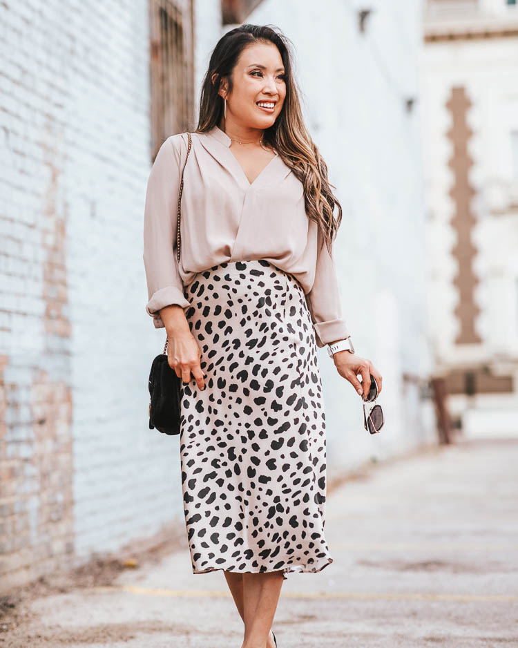 cute & little | popular dallas fashion blog | morning lavender reagan leopard print midi skirt | work office style outfit | Best Leopard Print Midi Skirts Under $50 by popular Dallas petite fashion blog, Cute and Little: image of a woman outside wearing a Nordstrom Wrap, Morning Lavender Reagan Beige Leopard Satin Midi Skirt, Nordstrom Rack Vince Alora Mule, Roll over image to zoom in SSMY Crossbody Bag for Womens Messenger Bag, ShopBop Gorjana 5 Disc Choker Necklace, Express Sparkle Cut Hoop Earrings, and Gucci GG 0106 S- GG0106S Sunglasses 56mm.  