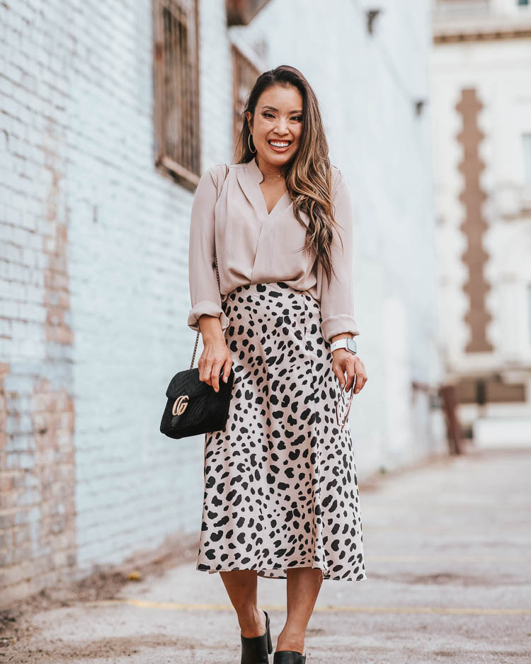cute & little | popular dallas fashion blog | leopard print midi skirt | work office style outfit | Best Leopard Print Midi Skirts Under $50 by popular Dallas petite fashion blog, Cute and Little: image of a woman outside wearing a Nordstrom Wrap, Morning Lavender Reagan Beige Leopard Satin Midi Skirt, Nordstrom Rack Vince Alora Mule, Roll over image to zoom in SSMY Crossbody Bag for Womens Messenger Bag, ShopBop Gorjana 5 Disc Choker Necklace, Express Sparkle Cut Hoop Earrings, and Gucci GG 0106 S- GG0106S Sunglasses 56mm.  