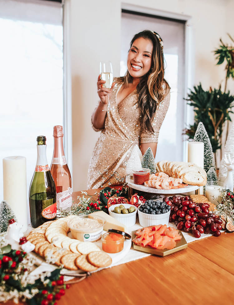 cute & little | dallas mom lifestyle blog | how to throw no-cook holiday new years party whole foods affordable | How-To Throw Holiday Party with No Cook Appetizers by popular Dallas life and style blog, Cute and Little: image of Whole Foods Tsar Nicoulai, Whitefish Roe American Golden, Whole Foods 365 Everyday Value, Assorted Entertainment Crackers, Whole Foods Hummus Original, Whole Foods Kitchen's Seafood Shrimp Cocktail Tail-on Shrimp w/ Cocktail Sauce, Whole Foods Bread Loaf Seeduction, Whole Foods Santa Barbara Smokehouse, Smoked Atlantic Salmon, Whole Foods Divina, Olives Casetelvetrano Organic and a woman holding a glass of champagne and wearing a gold sequin dress and Anthropologie Deepa Briar Embellished Headband.