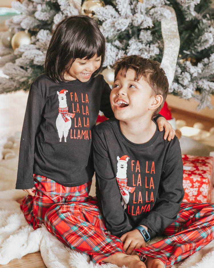 cute & little | dallas petite fashion blog | holiday gift guide cozy ideas | jcpenney budget affordable | family matching llama pajamas | Holiday Gift Guide: Cozy Gift Ideas by popular Dallas petite fashion blog, Cute and Little: image of two kids in front of a Christmas tree and wearing matching JcPenney holiday pajama sets.