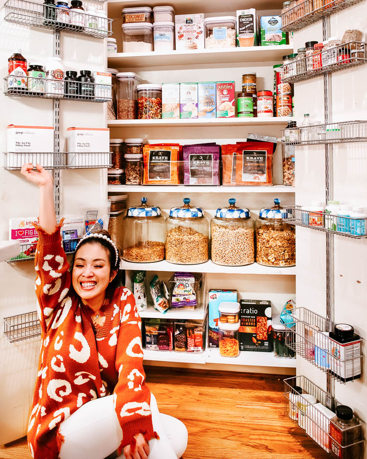 cute & little | dallas lifestyle blog | small pantry organization ideas tips | 5 Easy Tips for Small Pantry Organization by popular Dallas lifestyle blog, Cute and Little: image of a woman sitting in front of her organized small pantry and wearing a Amaryllis Feline Festive Distressed Sweater, Lululemon Train Times Pant 25", Amazon willbond 4 Pieces Pearls Headbands White Faux Pearl Rhinestones, and Goodnight Macaroon 'VANESSA' SEQUINNED STAR DISTRESSED SNEAKERS. 