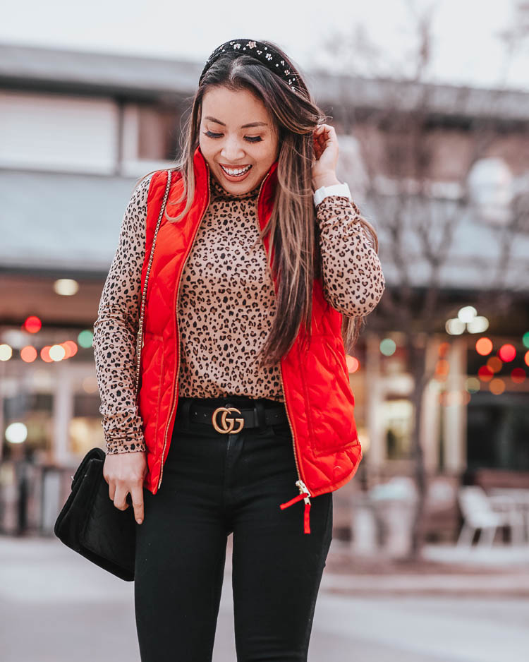 cute & little | dallas petite fashion blog | j.crew leopard turtleneck, red puffer quilted vest, black jeans | winter outfit | The Chic Headbands Trend by popular Dallas petite fashion blog, Cute and Little: image of a woman wearing a Loft EMBELLISHED HEADBAND, J. Crew Tissue turtleneck in leopard, J. Crew Excursion vest in recycled poly with PrimaLoft® fill, Gucci Leather belt with Double G buckle, American Eagle AE 360 NE(X)T LEVEL SUPER HIGH-WAISTED JEGGING, Fit Bit Versa Watch, and Nordstrom Vince Camuto Gigietta Bootie. 