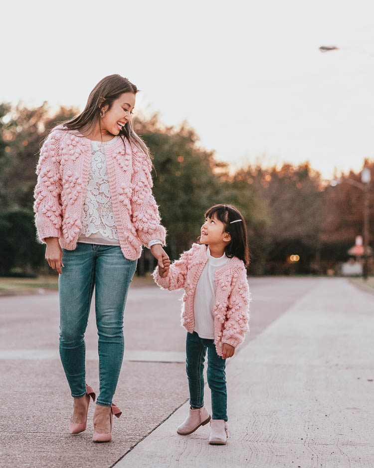 cute & little | dallas family mom blog | pink heart pom pom cardigan | mommy daughter twinning matching outfits valentines day | Valentine's Day Traditions by popular Dallas lifestyle blog, Cute and Little: image of a mom and daughter wearing pink shoes, Chicwish Knit Your Love Cardigan in Pink, American Eagle AE SUPER HIGH-WAISTED JEGGING, and H&M 7-pack Hair Clips.