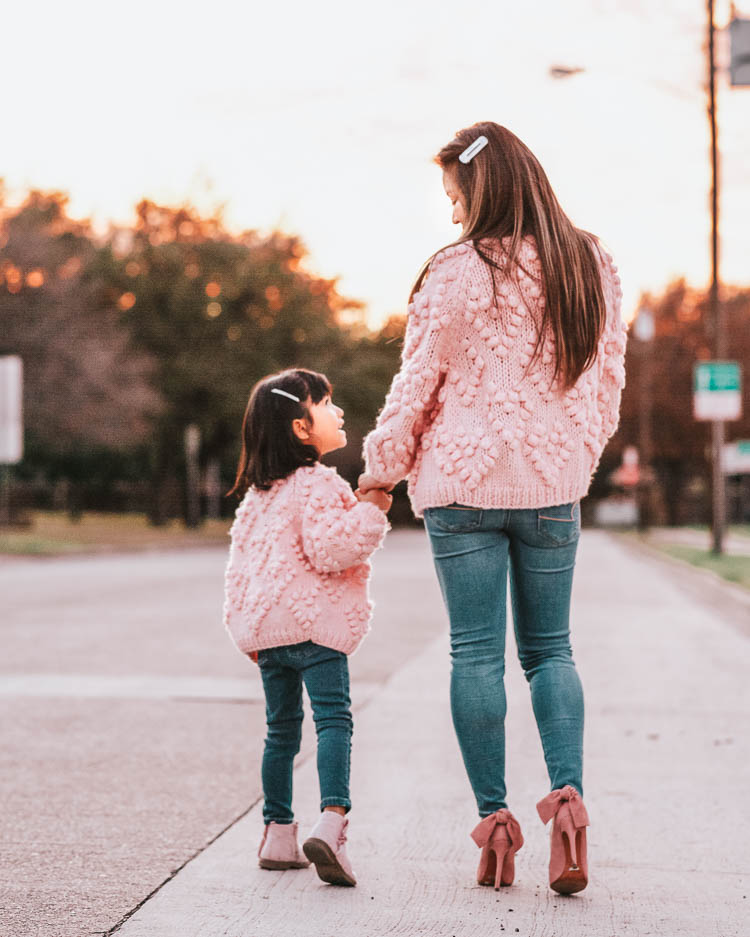 cute & little | dallas family mom blog | pink heart pom pom cardigan | mommy daughter twinning matching outfits valentines day | Valentine's Day Traditions by popular Dallas lifestyle blog, Cute and Little: image of a mom and daughter wearing pink shoes, Chicwish Knit Your Love Cardigan in Pink, American Eagle AE SUPER HIGH-WAISTED JEGGING, and H&M 7-pack Hair Clips.