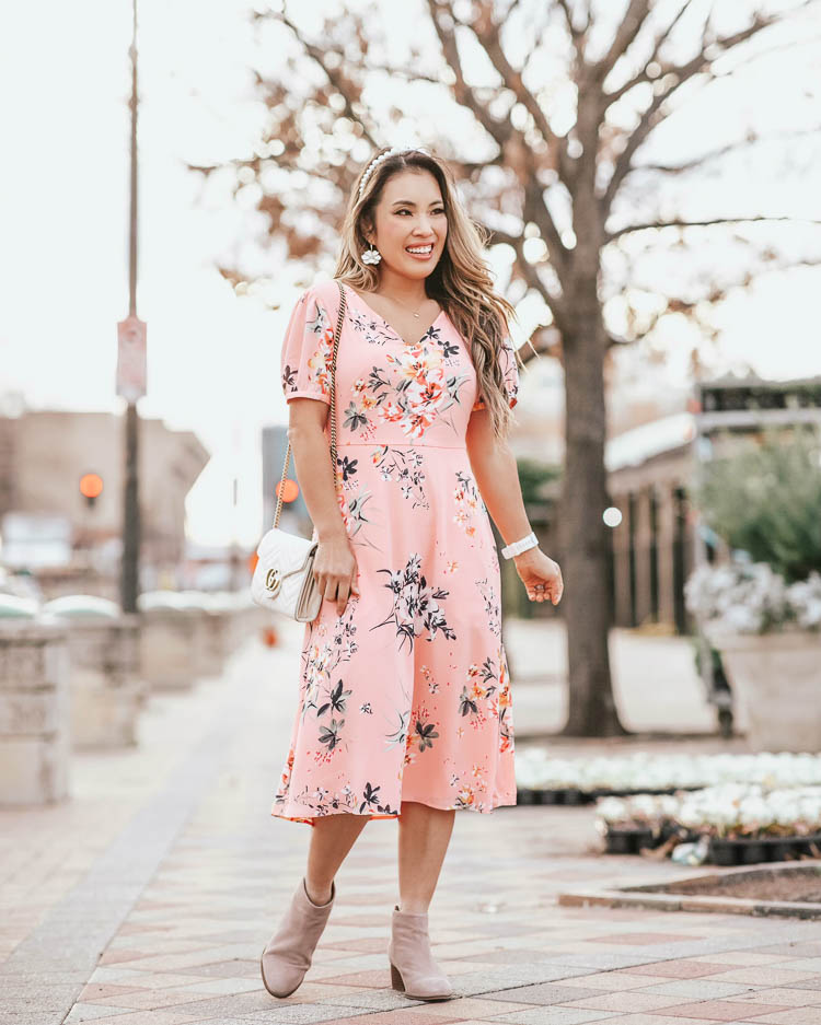 cute & little blog | dallas petite fashion | loft pink floral midi dress | spring outfit | Loft Sale by popular Dallas petite fashion blog, Cute and Little: image of a woman walking down a city street and wearing a Loft FLORAL SMOCKED BACK MIDI DRESS, Loft SEYCHELLES SUEDE FLOODPLAIN BOOTIES, Neiman Marcus GG Marmont Chevron Quilted Leather Flap Wallet on a Chain, Amazon Navachi 18k Gold Plated White Enamel Flower Crystal Az2461e Hoop Earrings, and Amazon WILLBOND pearl headband.