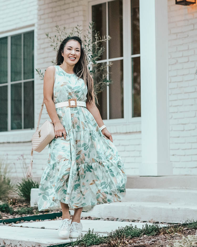 cute & little | dallas petite fashion blog | target spring dress april try-on haul | who what wear green floral dress| Target Summer Dresses by popular Dallas petite fashion blog, Cute and Little: image of a woman standing outside and wearing a Target A New Day Tiered Dress, Target Leather Woven Belt, Trask ‘Lindsey’ Sneakers, Amazon Pearl Clip Set, Fitbit ‘Versa’ Lite, and holding an Amazon clear tote bag. 