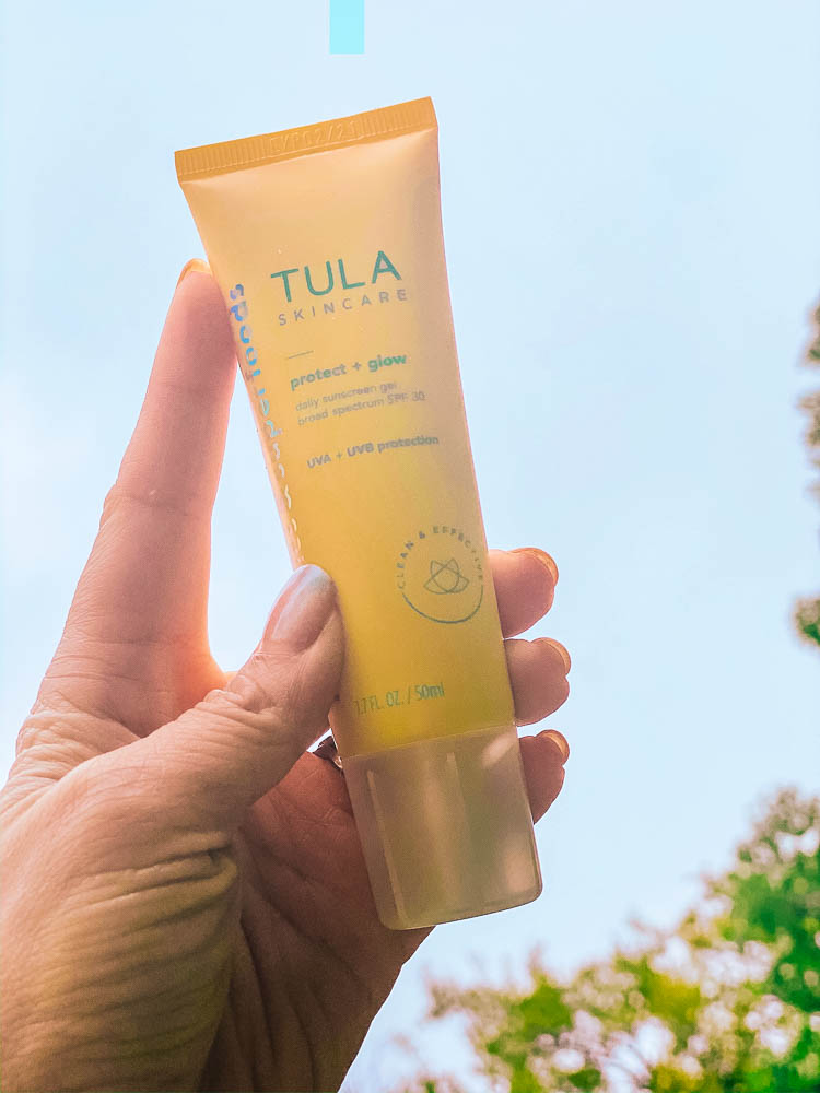 cute & little | dallas beauty blog | anti-aging morning skincare routine order 30s | tula protect glow daily sunscreen review | Morning Skin Care Routine by popular Dallas beauty blog, Cute and Little: image of a woman holding a tube of Tula Skincare protect + glow. 