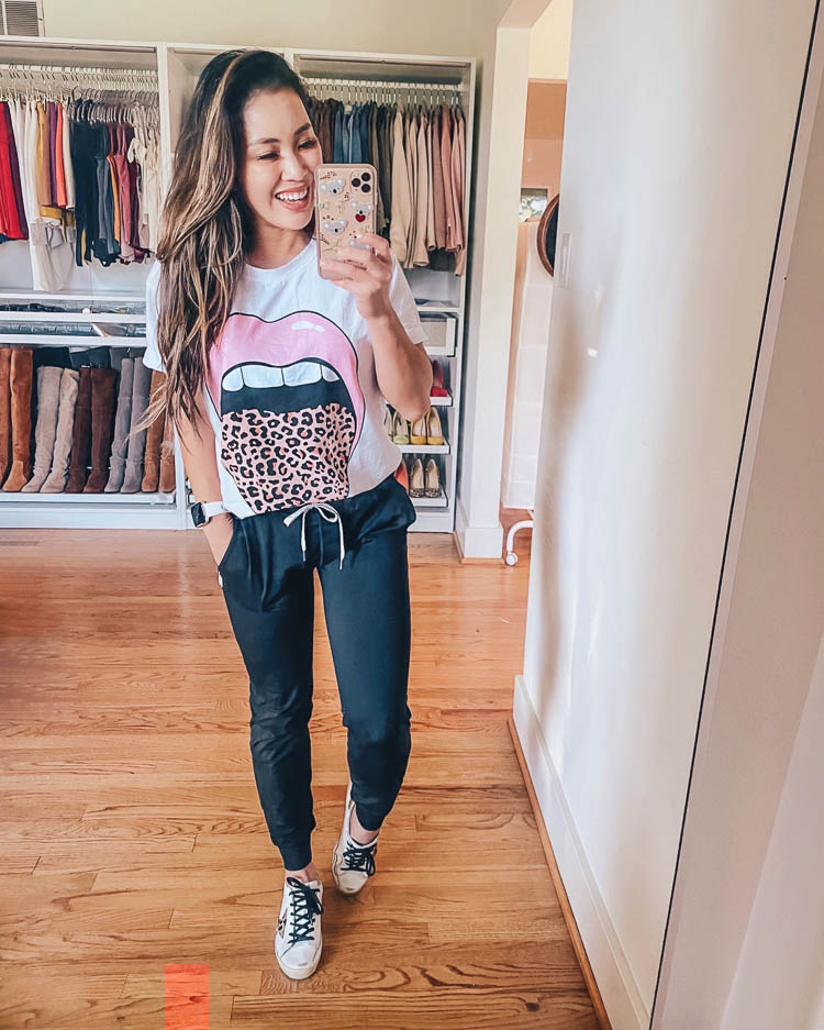 cute & little | dallas petite fashion blog | how to style joggers outfit ideas | amazon graphic rock band tee | How to Style Joggers by popular Dallas petite fashion blog, Cute and Little: image of a woman wearing a Amazon Rock Band Tee,  Vuori Performance Joggers, white leopard star sneakers, and holding a phone in a Sonix 'Koala Love' case.
