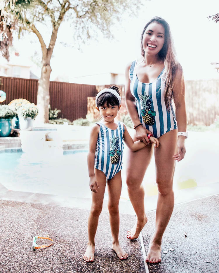 cute & little | mommy and me twinning pineapple swimsuits | best of memorial day sales 2020 | Memorial Day Sales by popular Dallas life and style blog, Cute and Little: image of a mom and her daughter standing by the pool and wearing Amazon C&M Wodro Family Matching Swimwear One Piece Swimsuits Pineapple Printed Monokini Bathing Suit and Etsy VeryShine thin fabric front knot pearl decorated fashion headband.