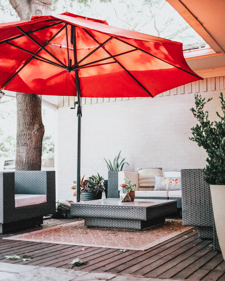 cute & little | dallas fashion lifestyle blogger | backyard patio | Backyard Patio by popular Dallas life and style blog, Cute and Little: image of a outdoor sectional next to a woven indoor/outdoor rug under a Lowe's Simply Shade Red Offset 11-ft Auto-tilt Octagon Patio Umbrella.