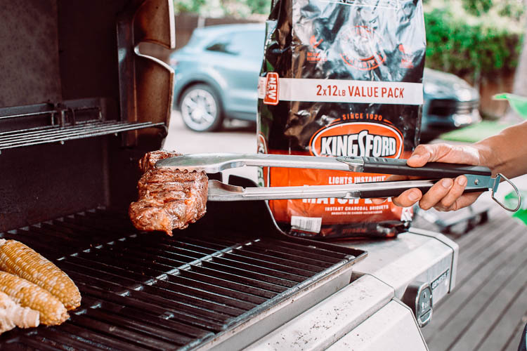 cute & little | dallas mom lifestyle blog | make awesome backyard summer memories | Kingsford Charcoal by popular Dallas lifestyle blog, Cute and Little: image of a man grilling meat and corn on the cob on a grill next to a bag of Kingsford Charcoal. 