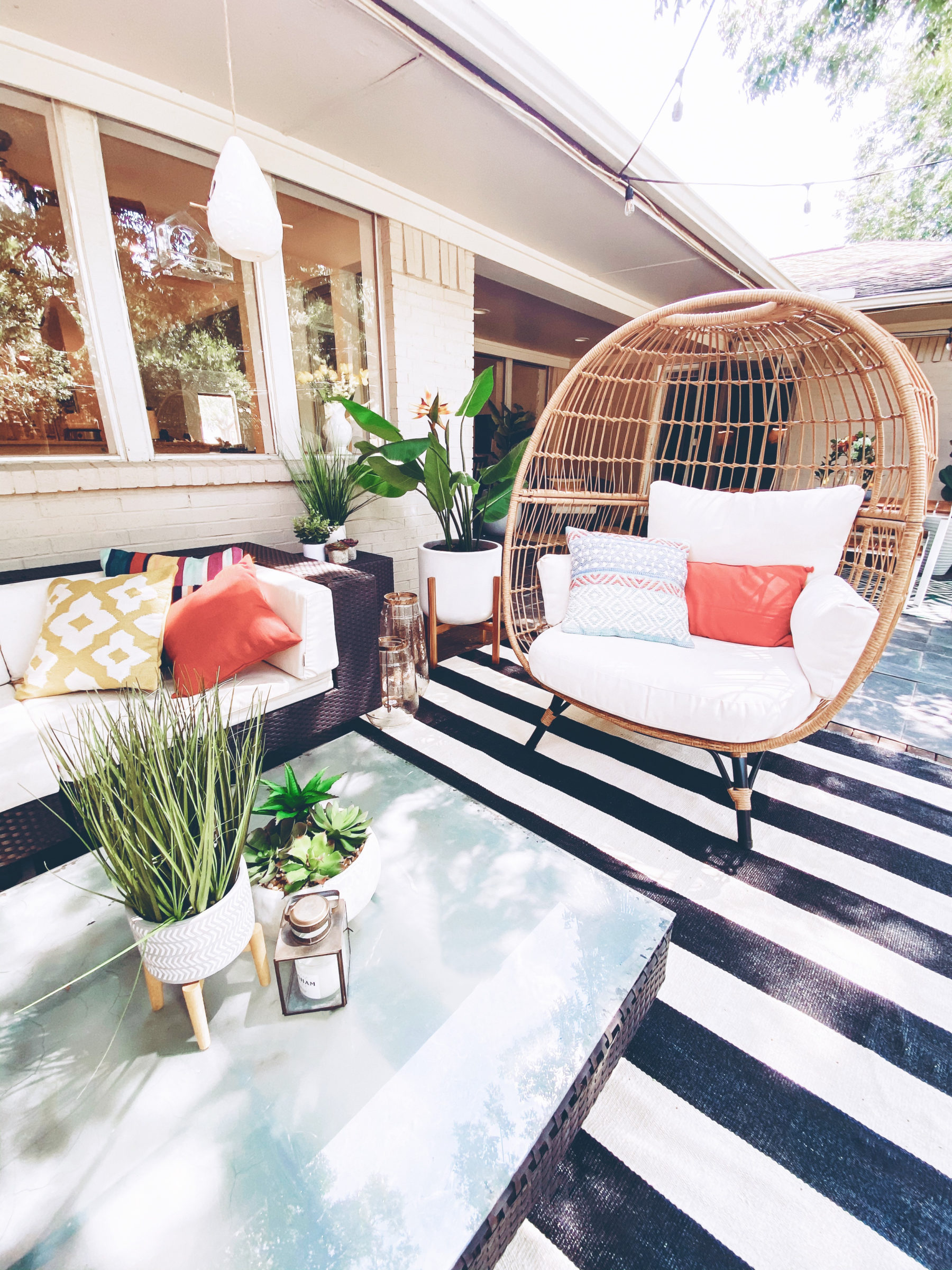 cute & little | dallas lifestyle blog | mid-century modern outdoor patio decorating ideas | egg chair, striped rug | Mid Century Modern Backyard by popular Dallas lifestyle blog, Cute and Little: image of a backyard decorated with a Target Southport Patio Egg Chair, World Market Ceramic Sevilla Outdoor Planter, Boutique Rugs Douds Area Rug, West Elm Simple Wood Lanterns, Target Vickerman Artificial Potted Bird of Paradise Palm Tree, Pottery Barn Faux Potted Succulent in Ceramic Bowl, outdoor sectional couch and Target 12" x 10" Artificial Eucalyptus Plant Arrangement in Pot.