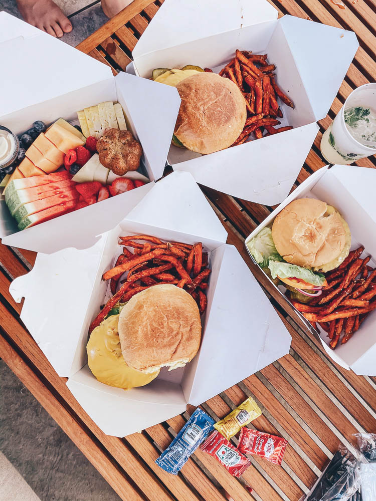 cute & little | dallas family mom travel blog | ritz-carlton dallas staycation | food poolside dining | Family Staycation by popular Dallas lifestyle blog, Cute and Little: image of white takeout boxes filled with cheeseburger, sweet potato fries, and fruit. 