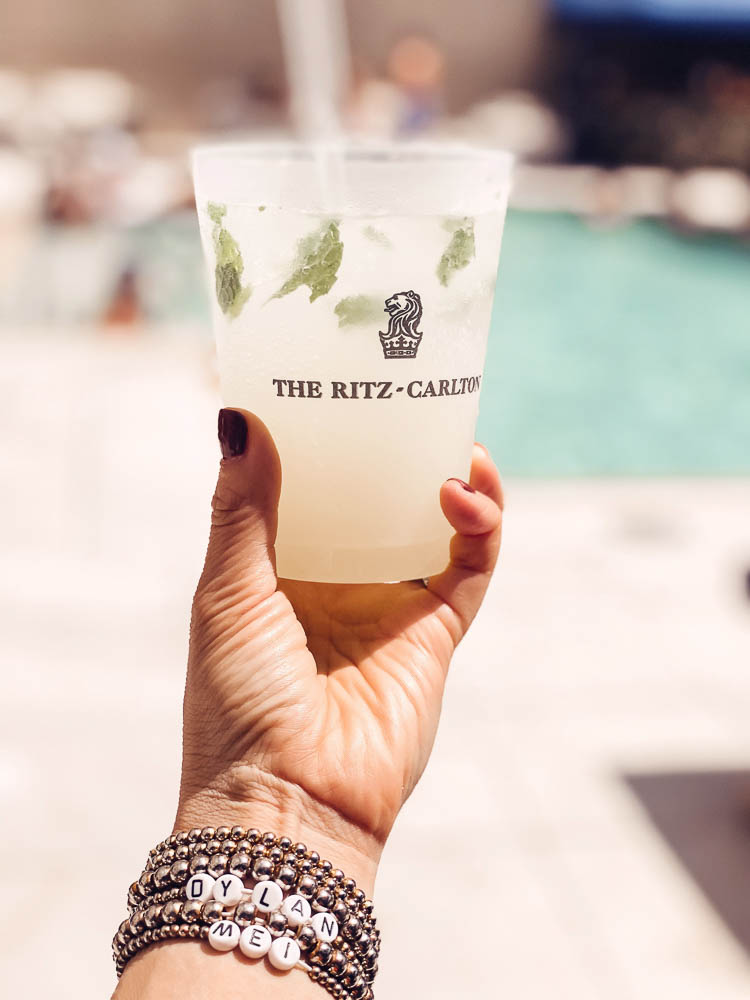 cute & little | dallas family mom travel blog | ritz-carlton dallas staycation | Family Staycation by popular Dallas lifestyle blog, Cute and Little: image of a woman wearing some DIY letter bracelets and holding a cup with The Ritz-Carlton logo on it.  