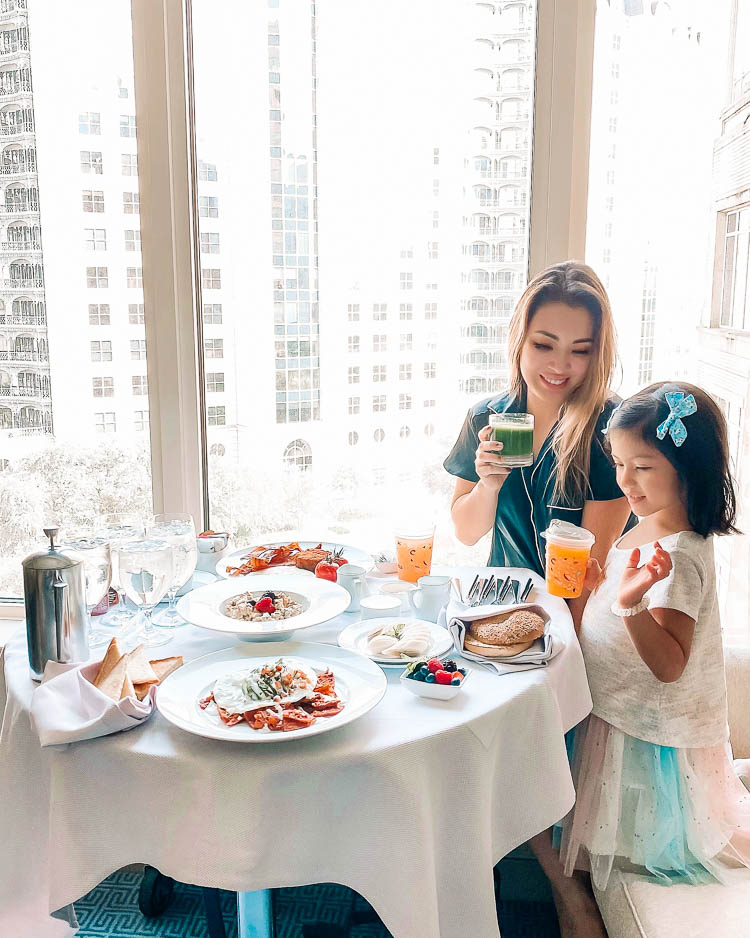 cute & little | dallas family mom travel blog | ritz-carlton dallas staycation | in-room dining service | Family Staycation by popular Dallas lifestyle blog, Cute and Little: image of a woman wearing Moonlight Dream Pajamas and sitting with her daughter at a table covered in various breakfast foods.