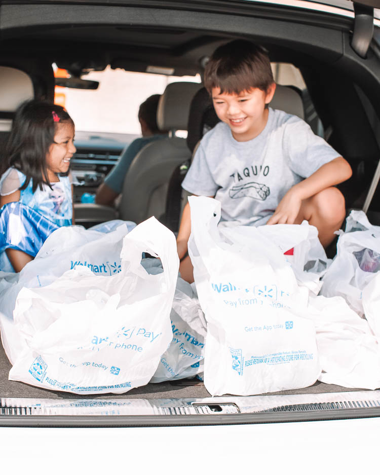 cute & little | dallas mom lifestyle blog | walmart online delivery grocery pickup review | Walmart Grocery Pickup Faq by popular Dallas lifestyle blog, Cute and Little: image of two kids sitting in he back of a car with some Walmart shopping bags. 