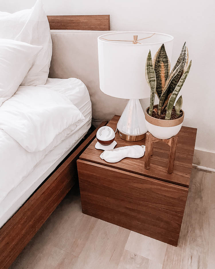 cute & little | dallas lifestyle blog | mid century modern master bedroom home nightstand decor | Mid Century Modern Bedroom by popular Dallas life and style blog, Cute and Little: image of a mid century modern night stand in a master bedroom with a West Elm Metalized Glass USB Table Lamp, snake tongue plant, Core sound machine, and Slip pure silk sleep mask.