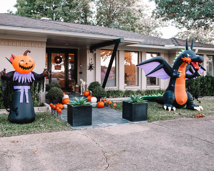 cute & little | dallas mom petite fashion blog | halloween front porch fall decor | walmart plus membership review |Walmart Halloween Decor by popular Dallas lifestyle blog, Cute and Little: image of a front porch decorated with a Walmart pumpkin wreath, pumpkin trio sign scarecrow, similar crates | similar light-up pumpkin similar 'hey pumpkin' doormat, buffalo check doormat giant spider, dog skeleton, inflatable pumpkin reaper, inflatable dragon, and pumpkin pathway lights.