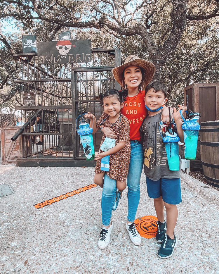 San Antonio Vacation by popular Dallas travel blog, Cute and Little: image of a woman wearing a Fifth Sun Graphic T Shirt Red Tacos and Cerveza,AE Ne(x)t Level High Waisted Jegging, Golden Goose sneakers, and Dos Femmes Topo Loco Earrings and standing with her two kids at the San Antonio Sea World. 