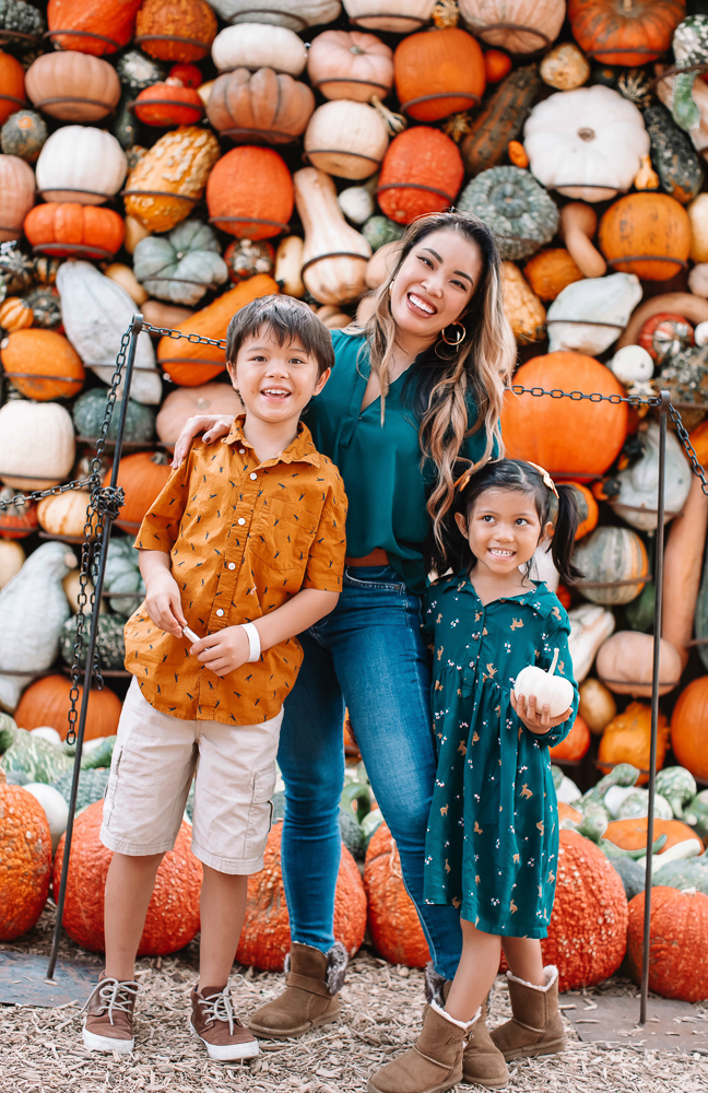 cute & little | dallas fashion blogger | fall coordinating family photo outfit ideas | dallas arboretum pumpkin patch village |Family Outfits by popular Dallas petite fashion blog, Cute and Little: image of a family sitting in a pile of pumpkins and wearing a green blouse, rust color polo, orange button up, brown fabric sneakers, Rvca jeans, American Eagle AE Ne(x)t Level High Waisted Jegging,BEARPAW Koko Buckle Strap Faux Fur & Genuine Sheepskin Lined Boot,Nike Killshot 2 Leather,BEARPAW Kids' Rosie Fashion Boot,The Children's Place Boys Pull-on Cargo Shorts, and green fox print dress. 