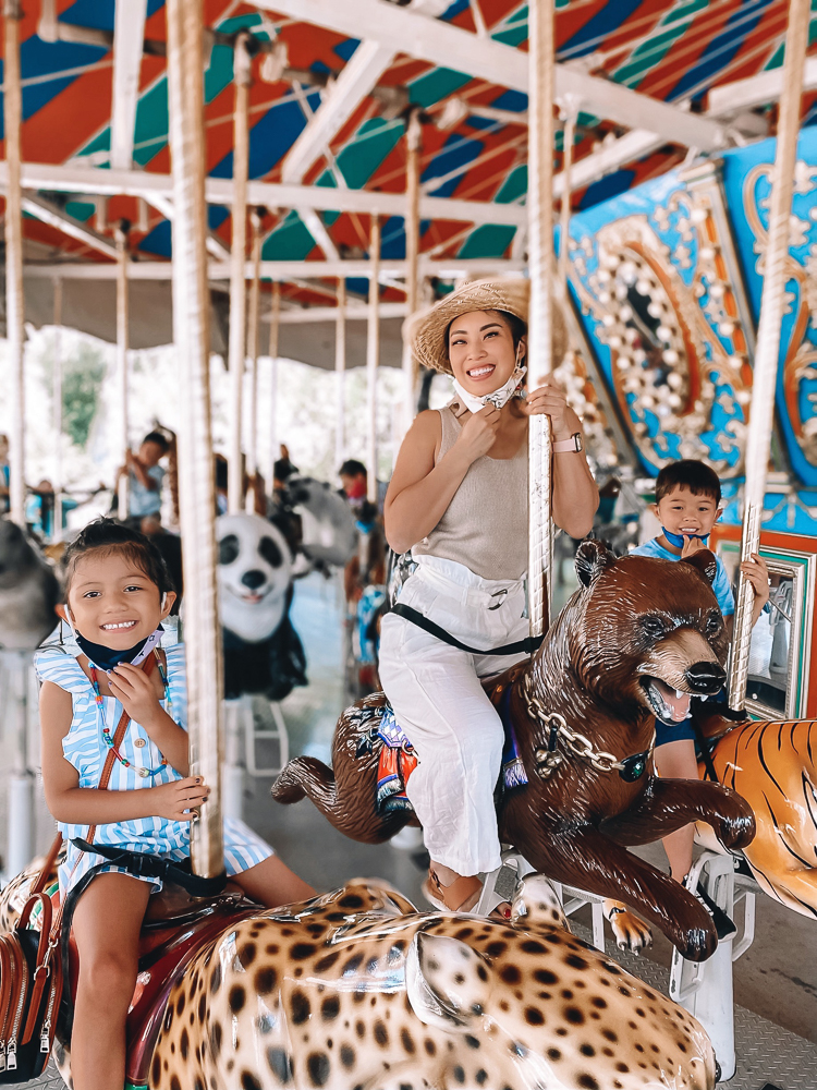 San Antonio Vacation by popular Dallas travel blog, Cute and Little: image of a mom and her two kids riding a merry-go-round at the San Antonio zoo. 