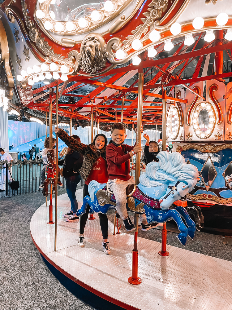 cute & little | dallas family mom blog | gaylord texas lone star christmas carousel review |Gaylord Texan by popular Dallas lifestyle blog, Cute and Little: image of a mom and her two kids riding a merry-go-round at the Gaylord Texan. 