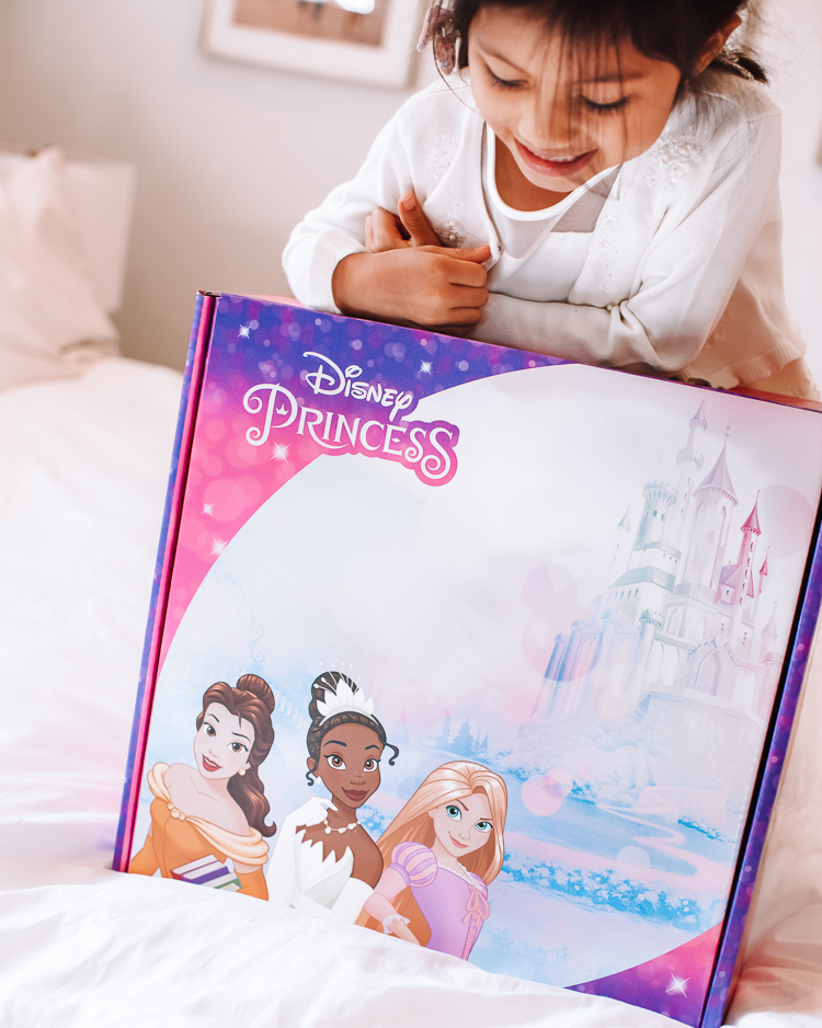 cute & little | dallas petite fashion blog | hasbro disney princess royal shimmer fashion doll unboxing review | girls holiday 2020 gift guide idea |Disney Princess Dolls by popular Dallas lifestyle blog, Cute and Little: image of a little girl sitting on her bed behind a Disney Princess dolls box. 