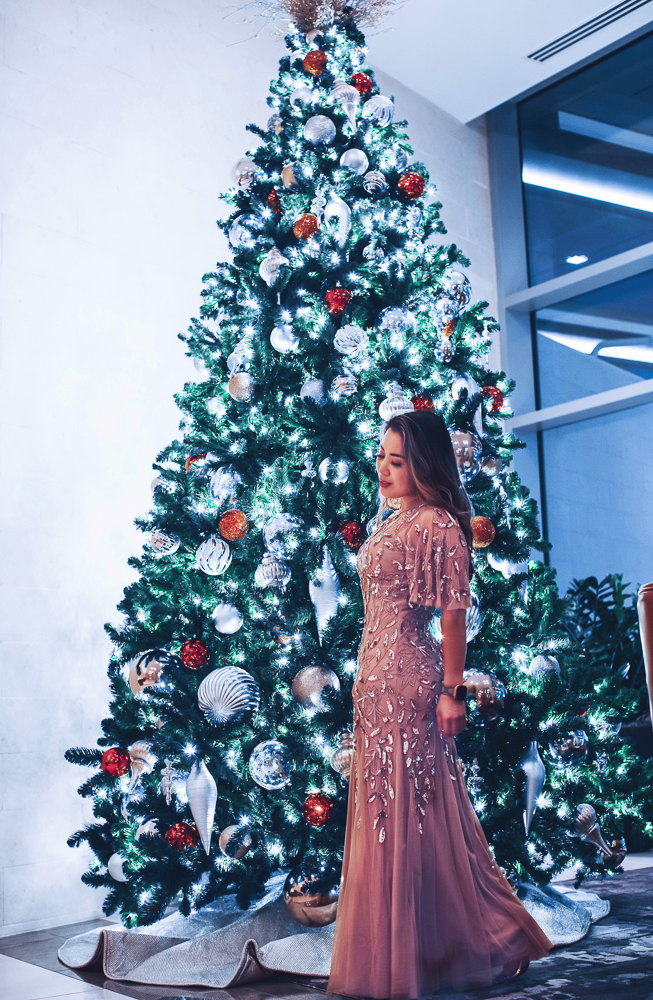 cute & little | dallas mom lifestyle blog | things to do frisco holidays 2020 | hyatt regency frisco review |Things to do in Frisco TX by popular Dallas travel blog, Cute and Little: image of a woman standing next to a Christmas tree at the Frisco Hyatt hotel. 