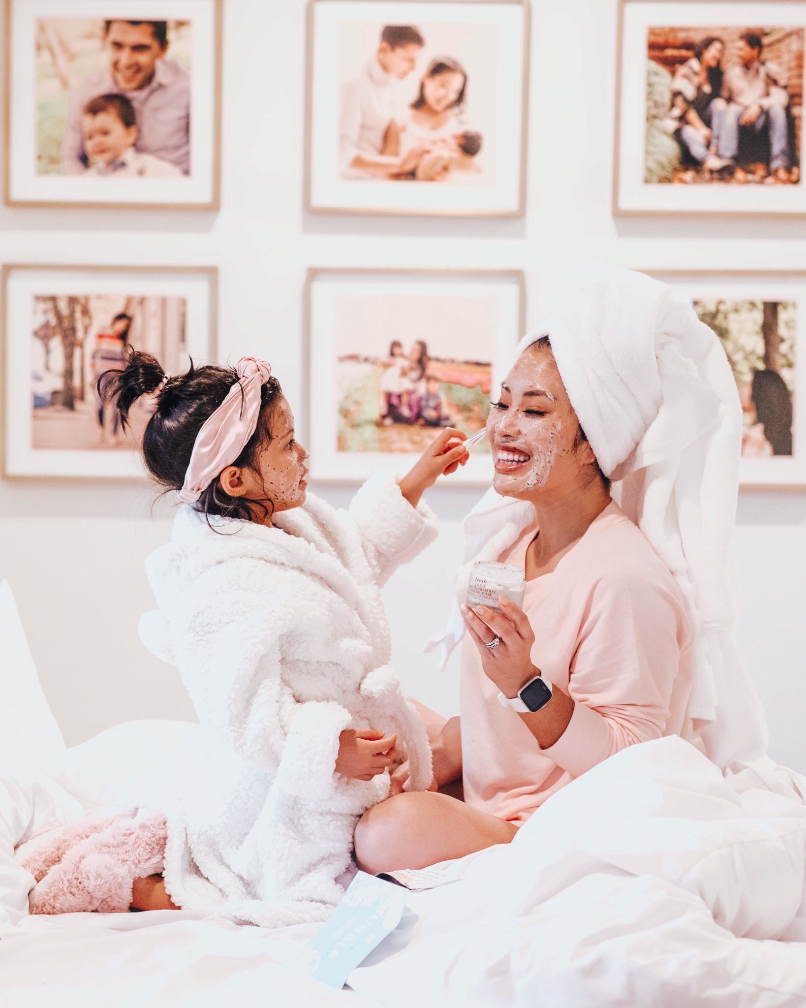 cute & little | dallas petite fashion blog | walmart beauty self care products must-have | Walmart Self Care Products by popular Dallas lifestyle blog, Cute and Little: image of a mom and her daughter sitting on a bed with white bedding and applying face masks. 