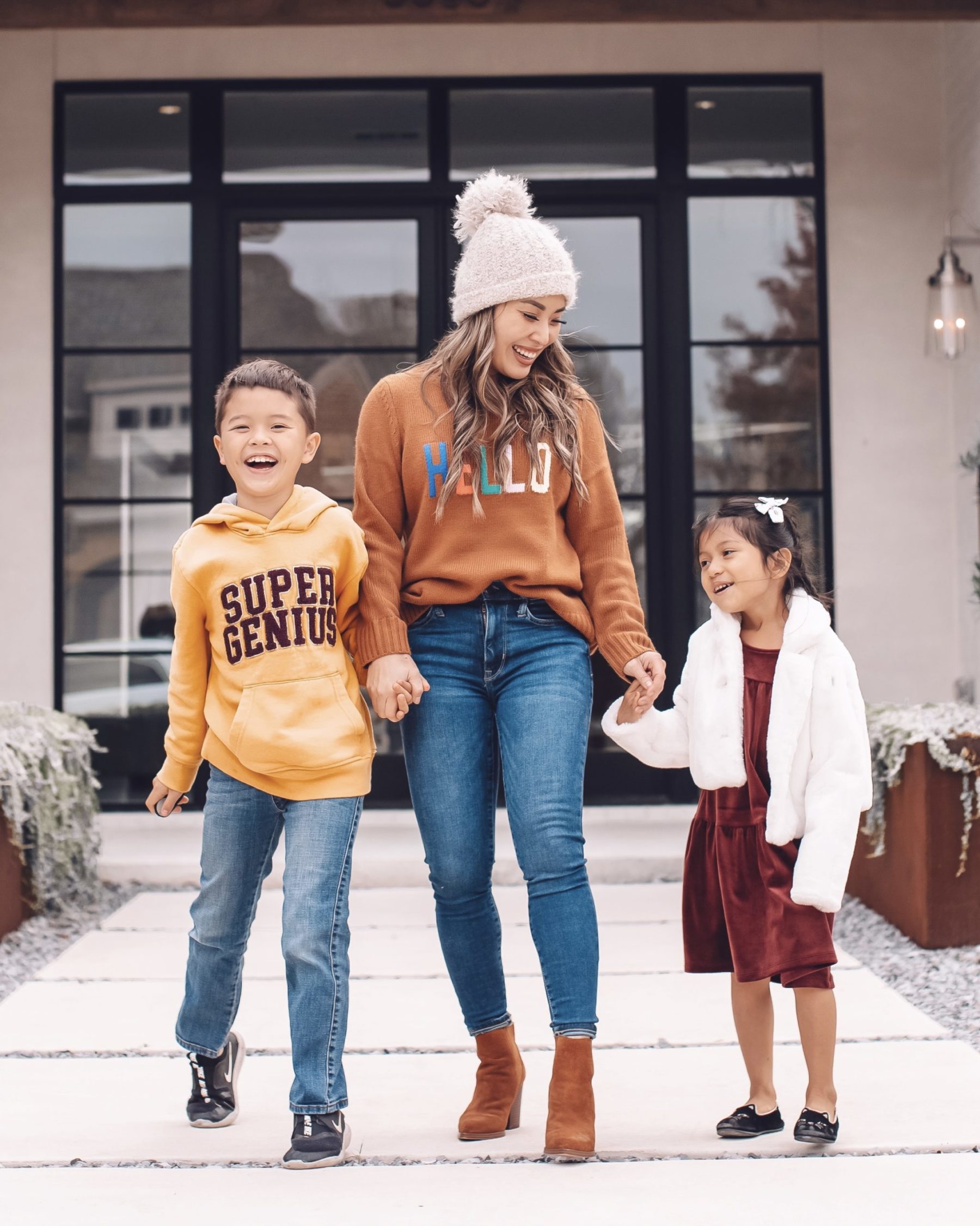cute & little | dallas petite fashion blog | how to create a home you love | life tips |Create a Home by popular Dallas life and style blog, Cute and Little: image of a mom standing outside with her son and daughter and wearing a Hello Sweater, brown suede ankle boots, jeans, Super Genius hoodie, cream pom beanie, Nike shoes, Tucker + Tate jeans, Velour dress, cat ballet flats, and white floral print hair bows. 