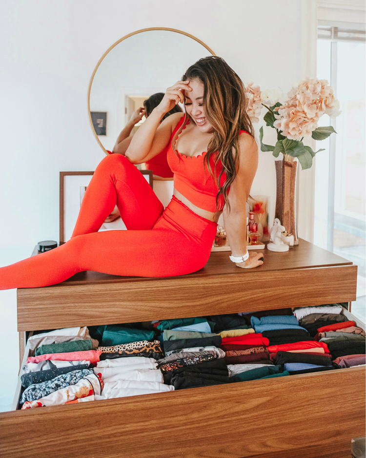 cute & little | dallas petite fashion blog | amazon closet organization essentials | dresser marie kondo organization |Amazon Organization Essentials by popular Dallas lifestyle Cute and Little: image of a woman wearing a red sports bra and red leggings and sitting on her dresser. 