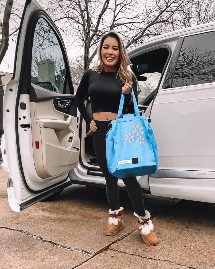 cute & little | dallas lifestyle blog | walmart kroger basket comparison | Walmart Basket Comparison by popular Dallas lifestyle blog, Cute and Little: image of a woman wearing a black long sleeve crop top, black leggings, UGG boots and holding a re-usable Walmart shopping bag while standing next to her car. 